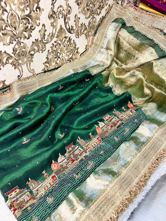 Emerald green Banarasi saree with hand embroidery of Varanasi ghats, boats, temples, and river scenes.