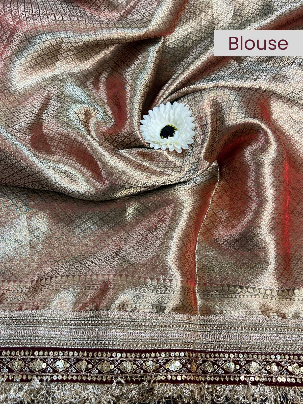 Close-up of a blouse fabric with a white flower pin, labeled 'Blouse'.
