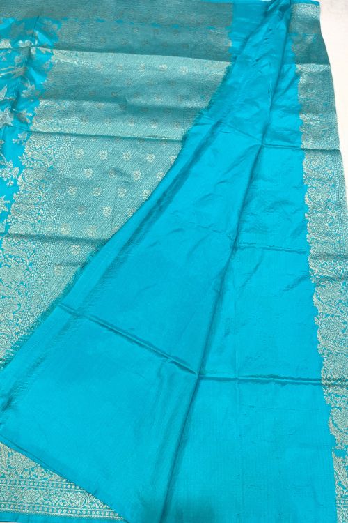 Handwoven Sky Blue Katan Silk Saree with allover floral jaal pattern, intricate sona rupa zari floral border and anchal, paired with a plain sky blue blouse piece featuring matching floral border sleeves, made in Banaras.