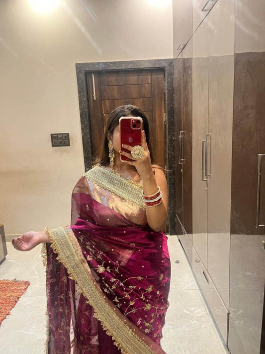 "Hand-embroidered Wine Banarasi tissue silk saree with intricate floral and bird motifs in gold zari and sequin work, finished with a delicate gold zari woven border."