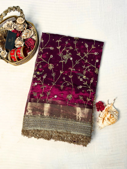 "Hand-embroidered Wine Banarasi tissue silk saree with intricate floral and bird motifs in gold zari and sequin work, finished with a delicate gold zari woven border."