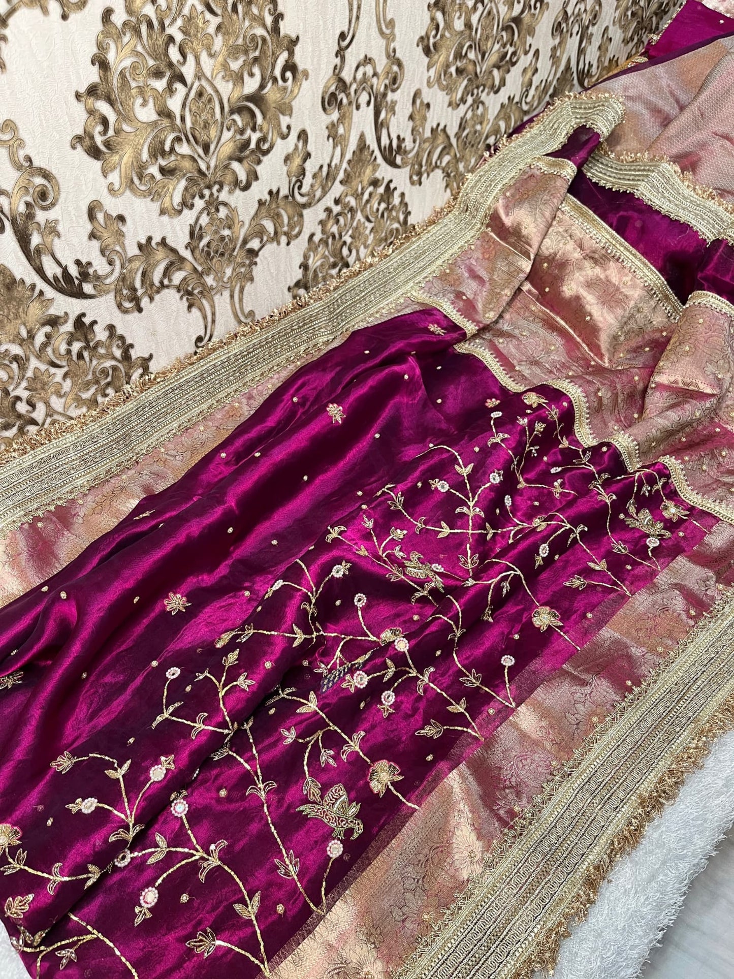 "Hand-embroidered Wine Banarasi tissue silk saree with intricate floral and bird motifs in gold zari and sequin work, finished with a delicate gold zari woven border."