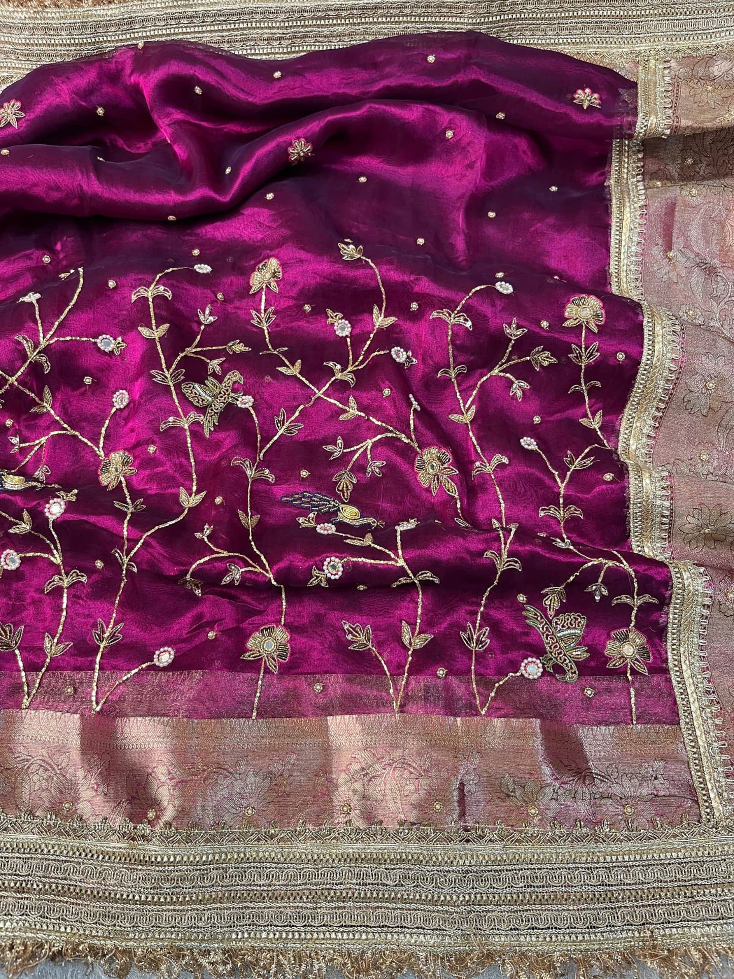 "Hand-embroidered Wine Banarasi tissue silk saree with intricate floral and bird motifs in gold zari and sequin work, finished with a delicate gold zari woven border."