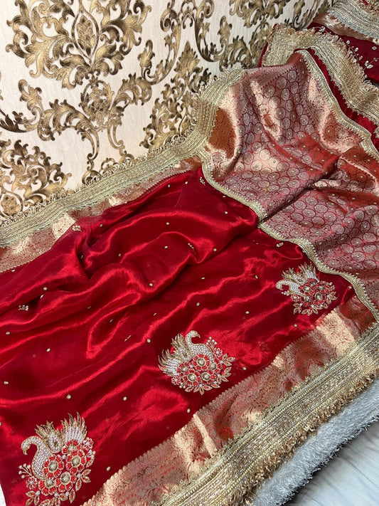"Red 100% pure Banarasi tissue silk saree featuring a beautifully embroidered white swan motif with floral detailing in silver and red. Adorned with scattered buti work, a richly woven zari pallu, and a gota patti lace border. Ideal for weddings, receptions, and festive occasions. Comes with an unstitched brocade blouse."