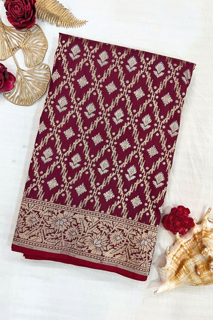 Handwoven wine color Katan silk saree with red contrast selvedge, intricate floral jaal pattern, and sona rupa zari floral border, paired with plain wine blouse piece featuring matching floral sleeve border, made in Banaras.