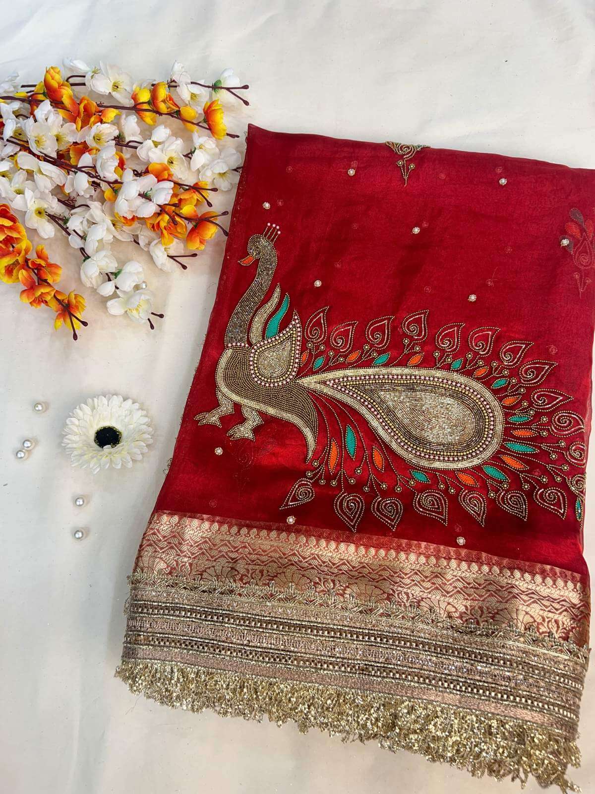 Red fabric with peacock design and gold border on a white background