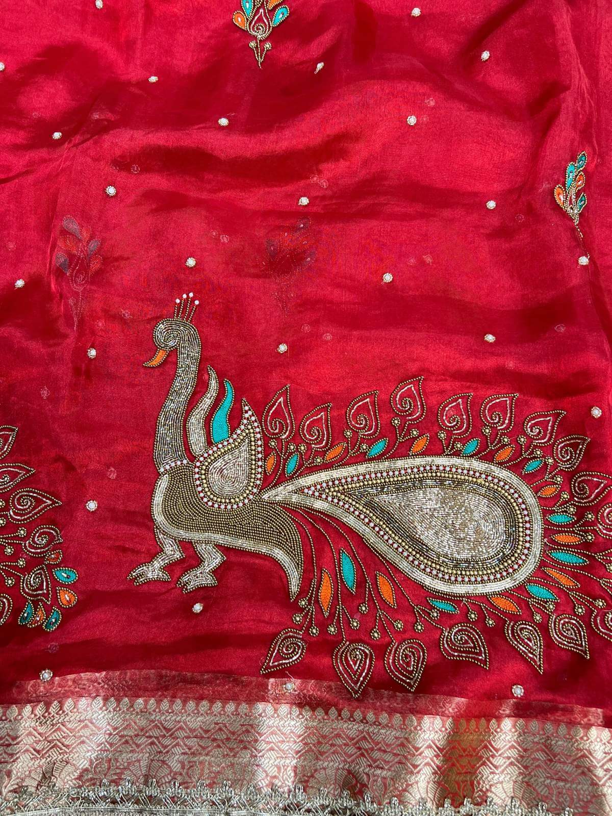 Red fabric with intricate peacock design and embellishments