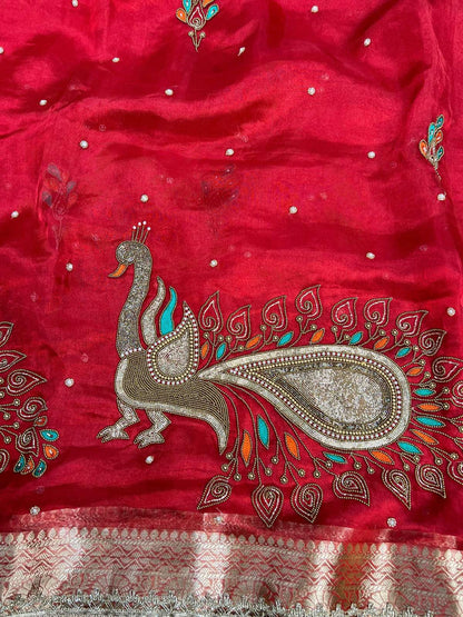 Red fabric with intricate peacock design and embellishments