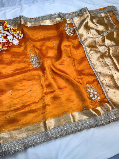 Orange saree with gold border and floral decorations on a white background