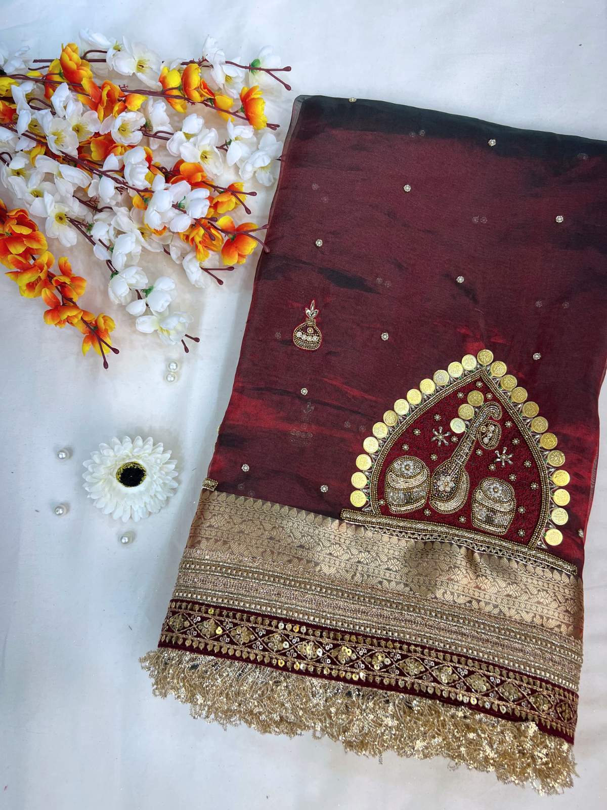 Decorative maroon fabric with gold embroidery on a white background