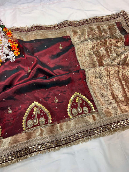 Maroon saree with gold embroidery on a white background