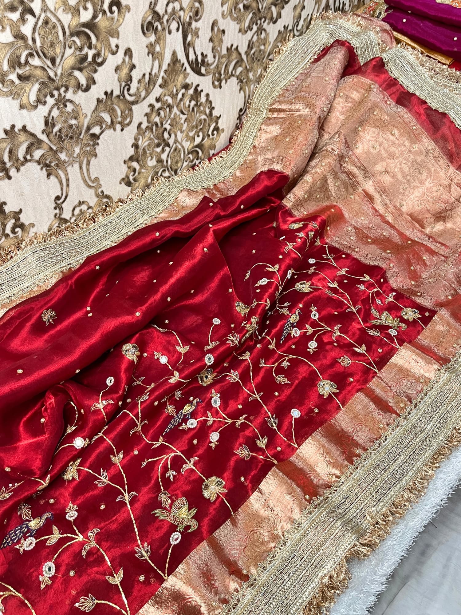 "Hand-embroidered red Banarasi tissue silk saree with intricate floral and bird motifs in gold zari and sequin work, finished with a delicate gold zari woven border."