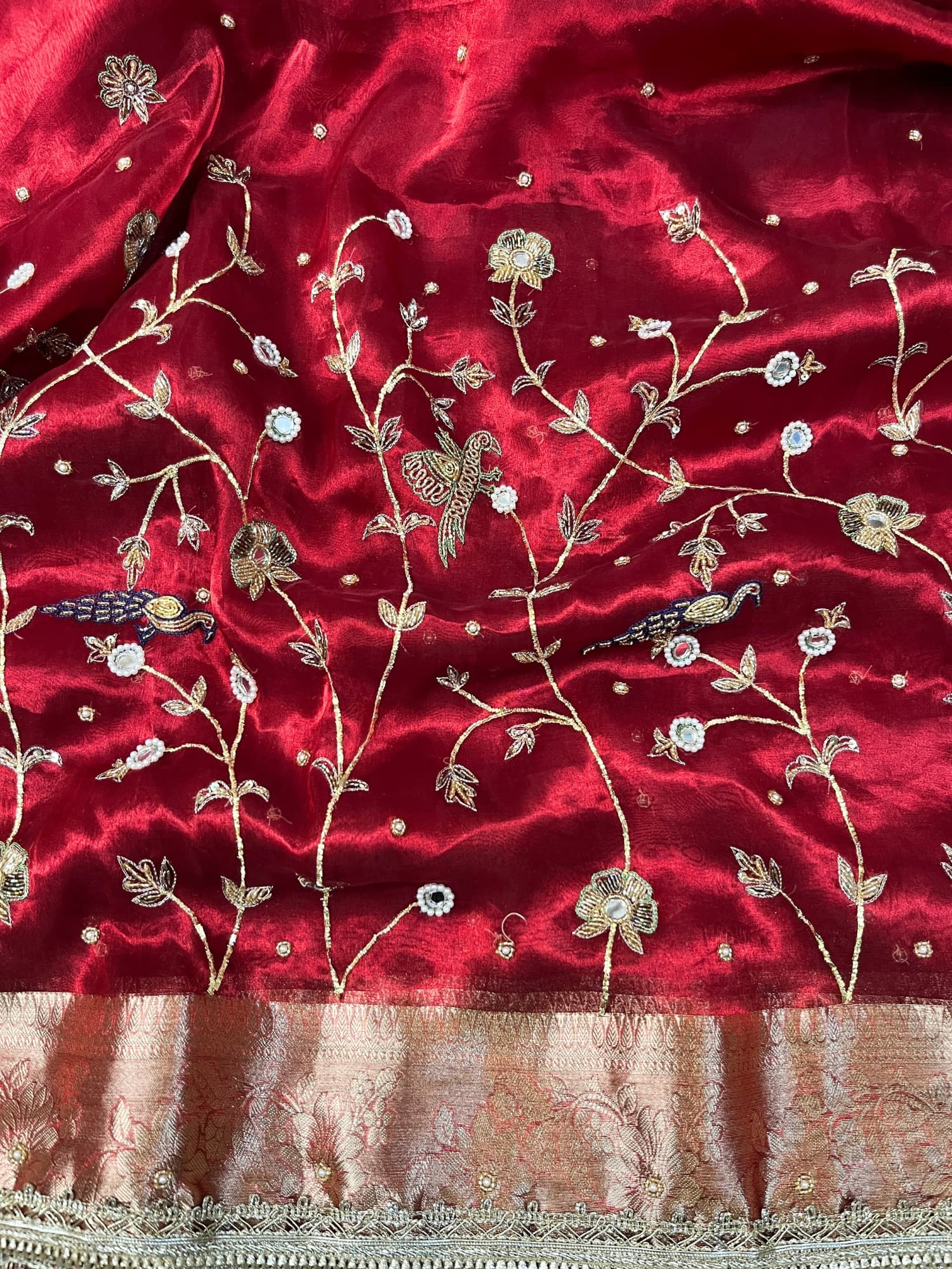 "Hand-embroidered red Banarasi tissue silk saree with intricate floral and bird motifs in gold zari and sequin work, finished with a delicate gold zari woven border."