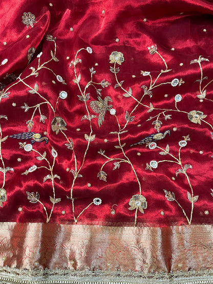 "Hand-embroidered red Banarasi tissue silk saree with intricate floral and bird motifs in gold zari and sequin work, finished with a delicate gold zari woven border."