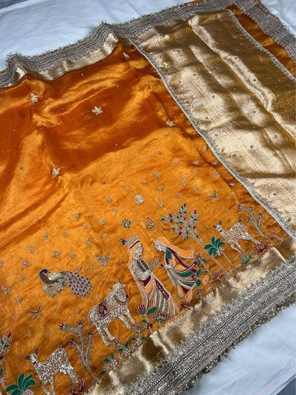 Orange Radha Krishna Banarasi silk saree featuring divine traditional artwork