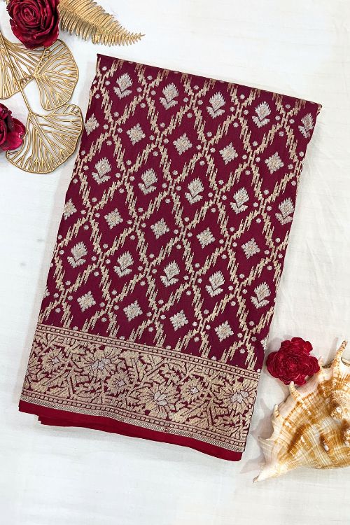 Handwoven wine color Katan silk saree with red contrast selvedge, intricate floral jaal pattern, and sona rupa zari floral border, paired with plain wine blouse piece featuring matching floral sleeve border, made in Banaras.