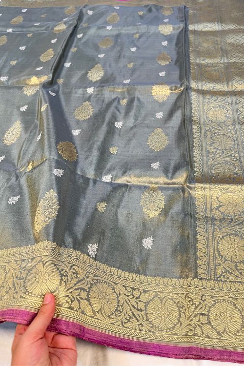 Grey Kora Tissue Silk Saree with gold and silver zari, Mughal floral border, and purple contrast selvedge – handwoven Banarasi saree.