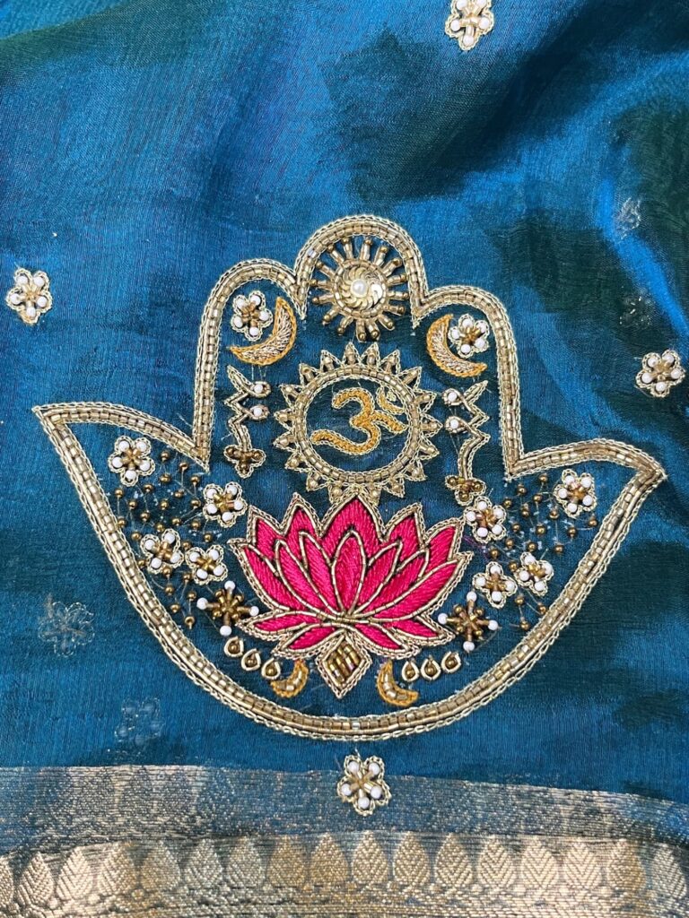 Blue Tissue Silk Saree with hand-embroidered Nazar motif featuring Om, lotus, floral, and moon designs in zari and threadwork